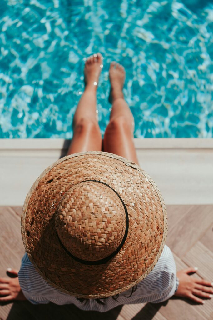 woman dangling legs in swimming pool 